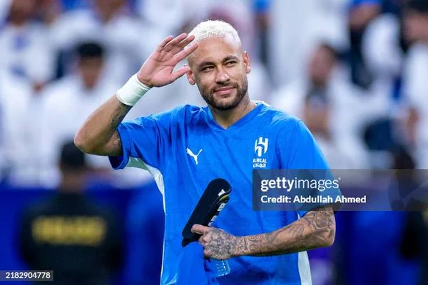 Neymar saluant la foule, cheveux blonds et maillot bleu, micro à la main (filigrane Getty Images).