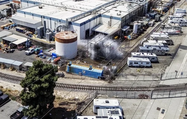 Vue aérienne du site industriel californien touché par la fuite de produits chimiques, avec un réservoir et des véhicules de loisirs garés.