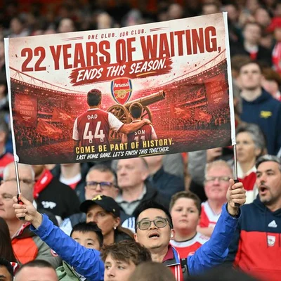 Un supporter brandit une banderole '22 ans d'attente' dans un stade en liesse.