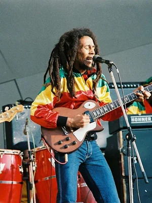 Bob Marley en concert, veste rasta et guitare électrique.