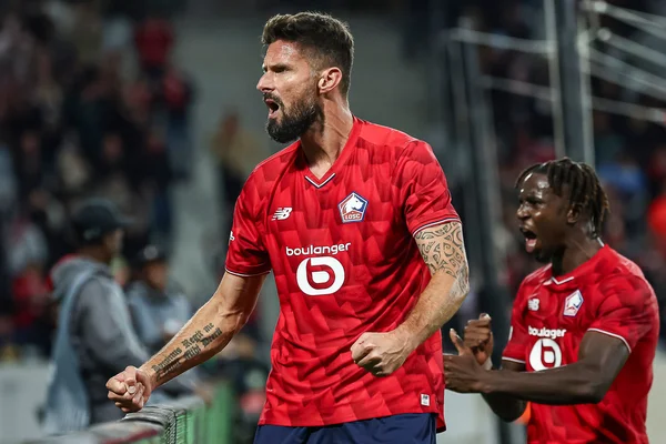 Olivier Giroud célébrant un but sous les couleurs du LOSC, acclamé par les supporters.