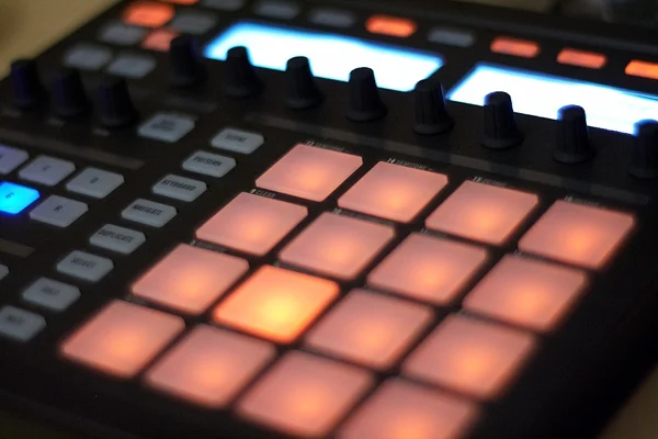 Gros plan du contrôleur Native Instruments Maschine avec pads orange.