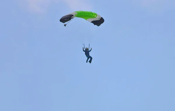 Parachutiste descendant sous un parachute noir, blanc et vert vif.
