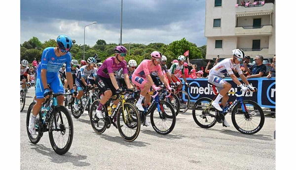 Le peloton du Tour d'Italie roule à vive allure sur une route bordée de spectateurs.