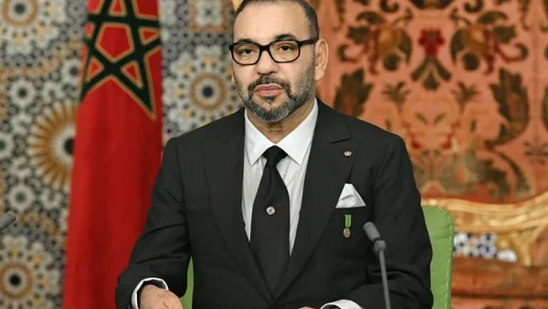 Le roi Mohammed VI assis devant le drapeau national du Maroc.