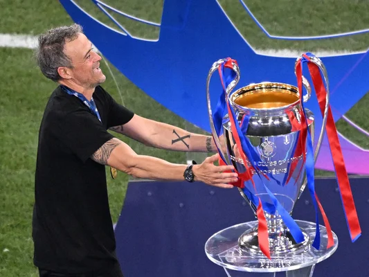 Luis Enrique touchant un trophée argenté aux couleurs du PSG.