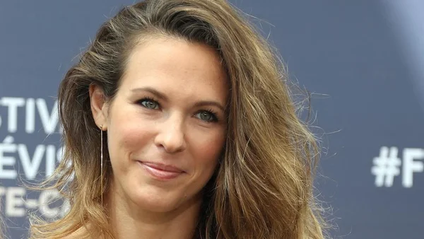 Lorie, portrait souriant avec une boucle d'oreille fine.