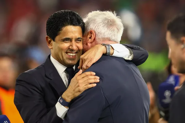 Nasser Al-Khelaïfi échangeant une accolade avec un collaborateur du PSG sur la pelouse.