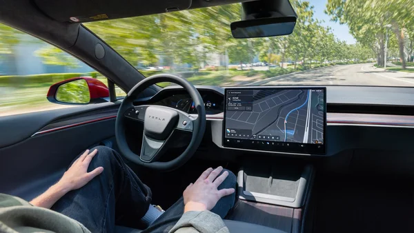 Tesla en conduite autonome, conducteur les mains libres, écran tactile central actif.