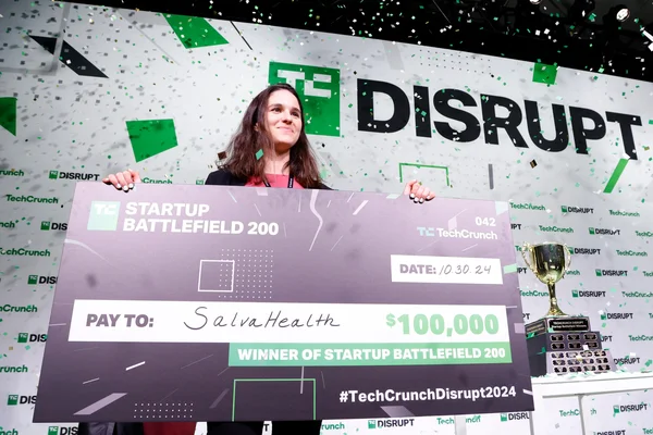 La gagnante de SalvaHealth brandissant un chèque de 100 000 $ lors du Startup Battlefield 200, sous une pluie de confettis.