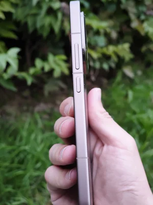 Le Xiaomi 15T Pro doré tenu en main, profil élancé devant un fond de verdure.