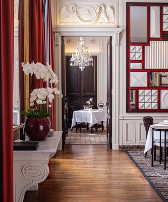 Salle à manger élégante du restaurant L'Ambroisie à Paris, avec son décor raffiné et son lustre en cristal.