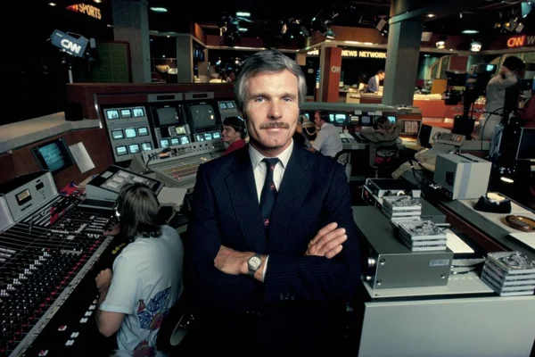 Ted Turner dans la régie de CNN, entouré d'écrans et de collaborateurs.