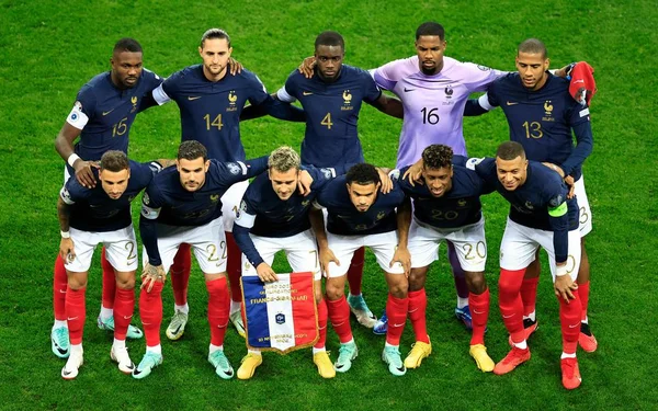 Photo d'équipe des Bleus avant un match, avec un joueur brandissant un drapeau tricolore.