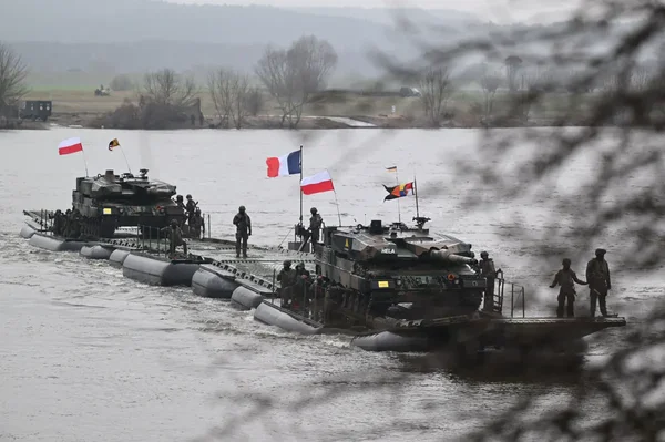 Chars de l'OTAN traversant un fleuve sur un pont de pontons lors d'un exercice militaire.