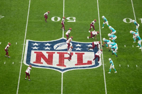 Vue aérienne d'un match de la NFL au Stade de France, avec le logo de la ligue au centre du terrain.