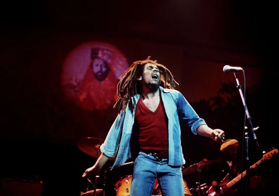 Bob Marley en concert, chemise bleue, tête renversée.