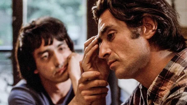 Scène du film 'Plus forts que le diable' : deux hommes dans une pièce, l'un en chemise à carreaux, l'autre en arrière-plan.
