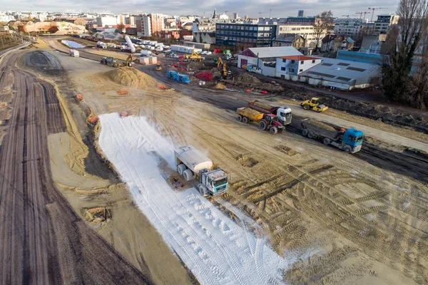 Vue aérienne du chantier du CDG Express avec engins lourds et géotextile blanc au sol.