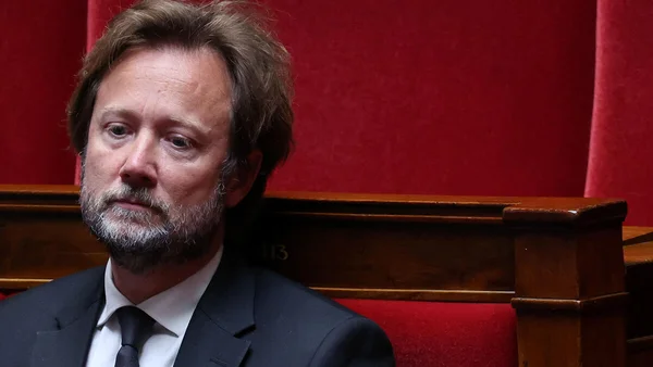Boris Vallaud posant devant un fond rouge.