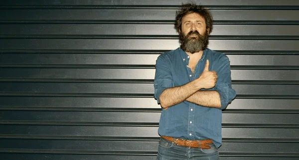 Quentin Dupieux, créateur compulsif, photographié devant un mur métallique.