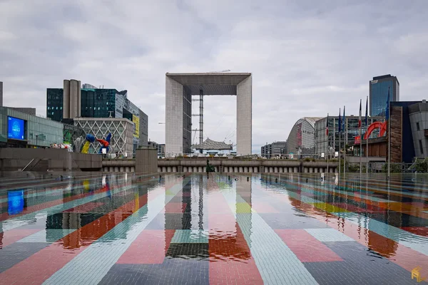 La Grande Arche de la Fraternité au cœur du quartier d'affaires de La Défense, avec un bassin réfléchissant au premier plan.