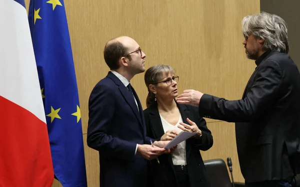 Discussion en intérieur avec les drapeaux français et européen en arrière-plan.