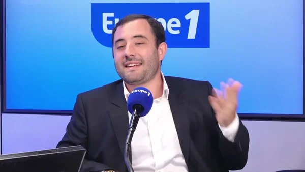 Charles Dennery interviewé sur Europe 1, micro à la main, geste appuyé.