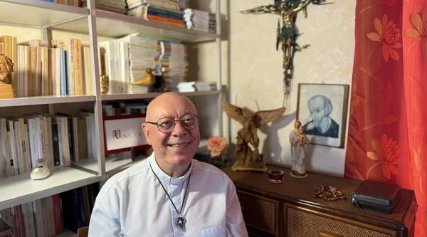 Un prêtre exorciste dans son bureau entouré de livres et d'objets religieux.
