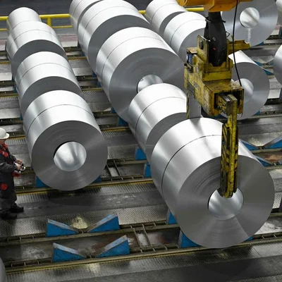 Bobines d'acier en usine, avec un pont roulant en action.