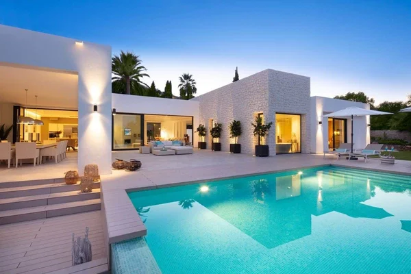 Villa de luxe moderne avec piscine illuminée, symbole des rénovations somptueuses offertes dans le scandale des syndics.