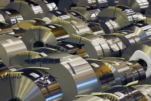 Rouleaux d'acier empilés dans un entrepôt industriel.
