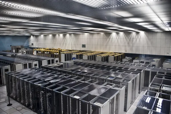 Intérieur d'un centre de données montrant des baies de serveurs vides et des équipements actifs.