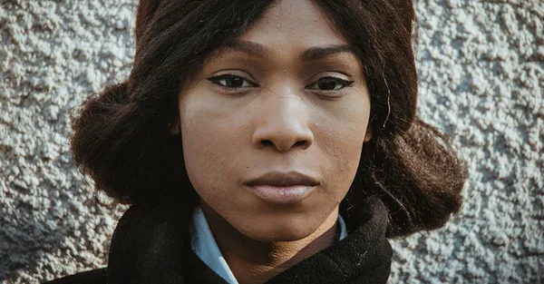 Assa Traoré en portrait devant un mur gris.