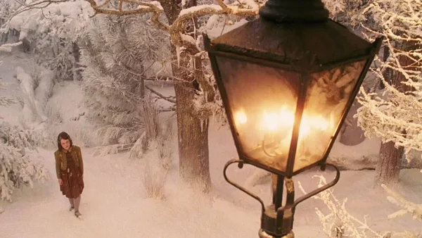 Scène du film Narnia : une jeune fille dans une forêt enneigée devant un réverbère illuminé.