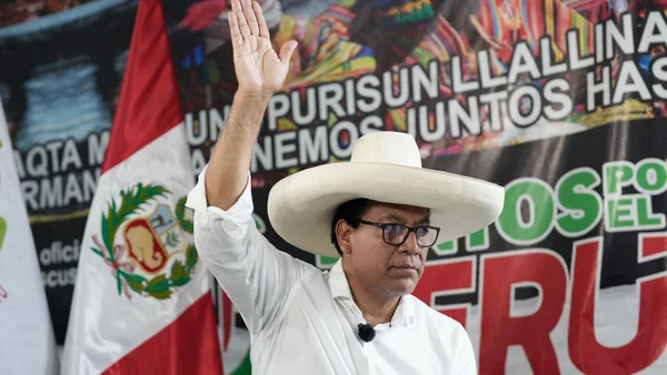 Roberto Sánchez devant le drapeau péruvien, main levée lors d'un événement.