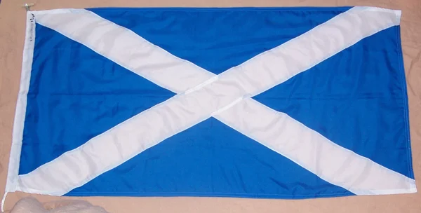 Le Saltire, drapeau national de l'Écosse, déployé sur une surface neutre.