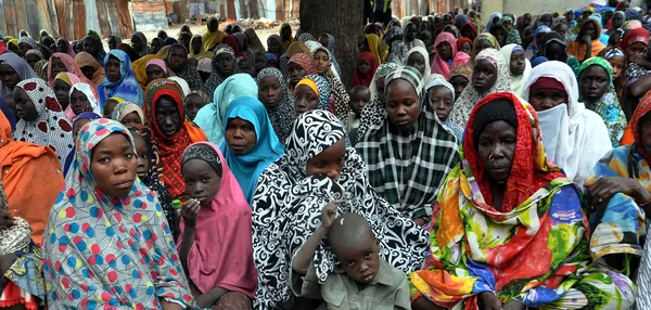 Foule de femmes et d'enfants rassemblés à l'extérieur dans un camp.