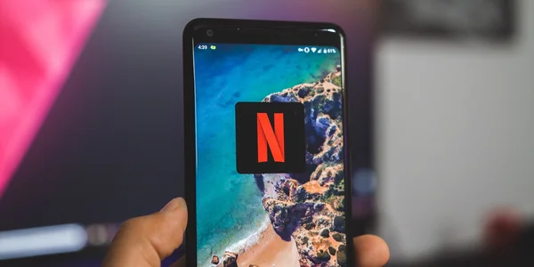 Un smartphone affichant l'application Netflix sur son écran, tenu à la main.