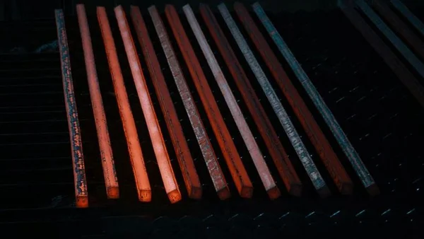 Barres d'acier incandescentes après laminage dans une aciérie.