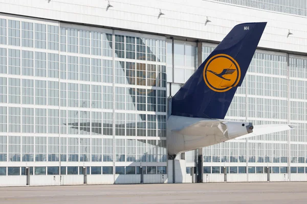 Queue d'un avion de Lufthansa garée devant un hangar à l'aéroport de Munich.