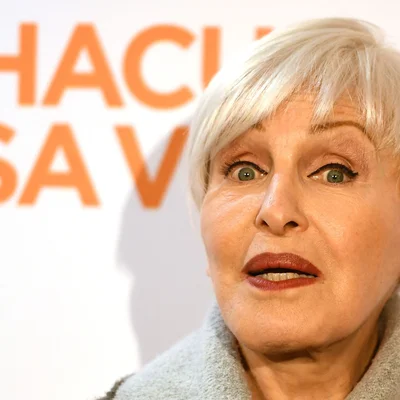 Nicole Croisille en manteau gris, regard franc.