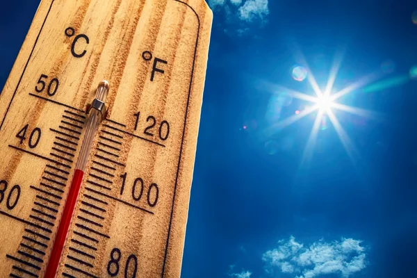 Thermomètre extérieur en bois indiquant une forte chaleur sous un soleil de plomb.