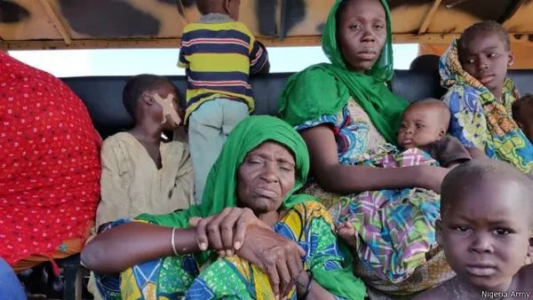 Femmes et enfants libérés, assis dans un véhicule militaire, avec un filigrane de l'armée nigériane.