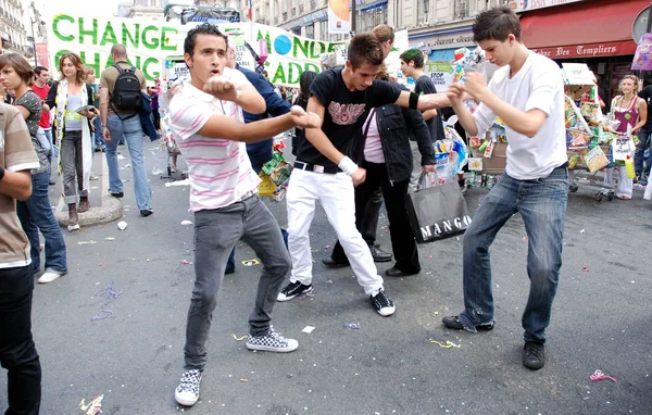 Danse Tecktonik en pleine rue lors d'un événement public à Paris, avec banderoles et public en arrière-plan.