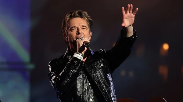 David Hallyday, rockeur en concert, veste de cuir et micro en main.