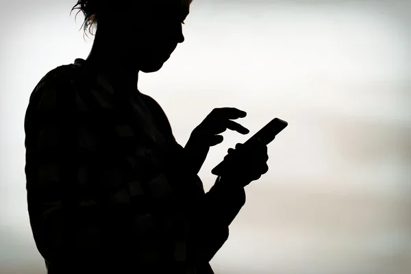 Silhouette d'une personne utilisant un smartphone, évoquant l'addiction aux écrans.