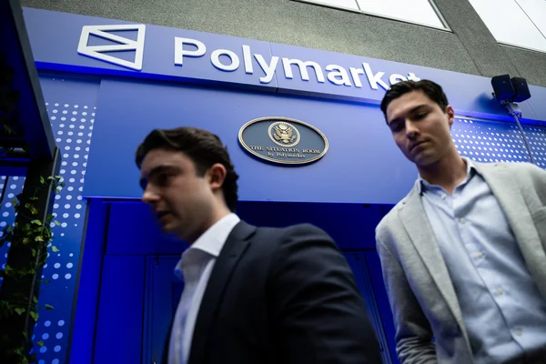 Deux hommes d'affaires devant le stand Polymarket intitulé 'The Situation Room'.