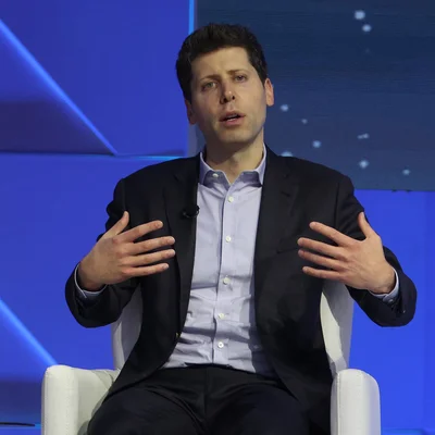 Sam Altman dans un fauteuil blanc, geste de la main, portrait professionnel.
