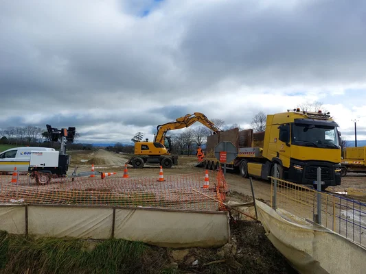 Travaux sur le chantier de l'A69 : une pelleteuse charge un camion sous un ciel nuageux.